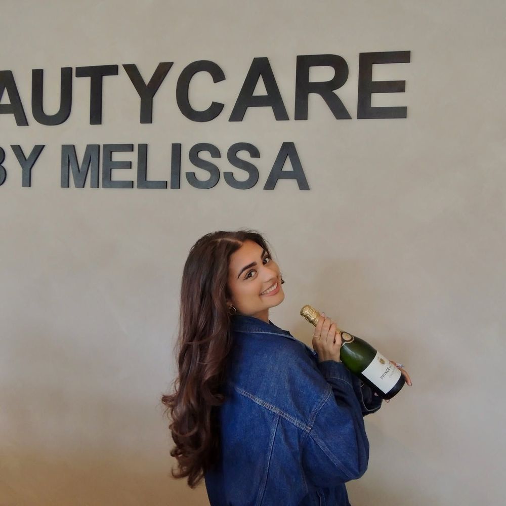Melissa op de opening van haar salon, onder de letters van Beautycare by Melissa